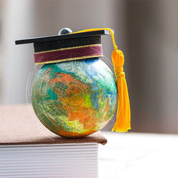 Tiny globe with graduation cap sitting on a book